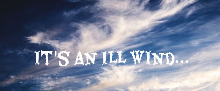 The words "IT'S AN ILL WIND" in a spiky font. The background is a dark blue sky with wind-swept white clouds.